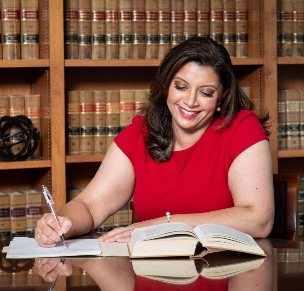 Smiling woman in red dress writing in law library, personal injury attorney at work