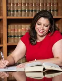 Smiling woman in red dress writing in law library, personal injury attorney at work