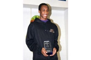 Athletic young man smiling, holding college sports award, wearing black hoodie with school logo
