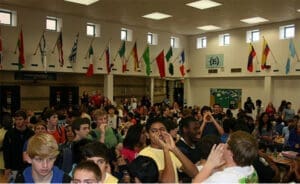 Crowded high school cafeteria with diverse students and international flags for attorney website alt text.