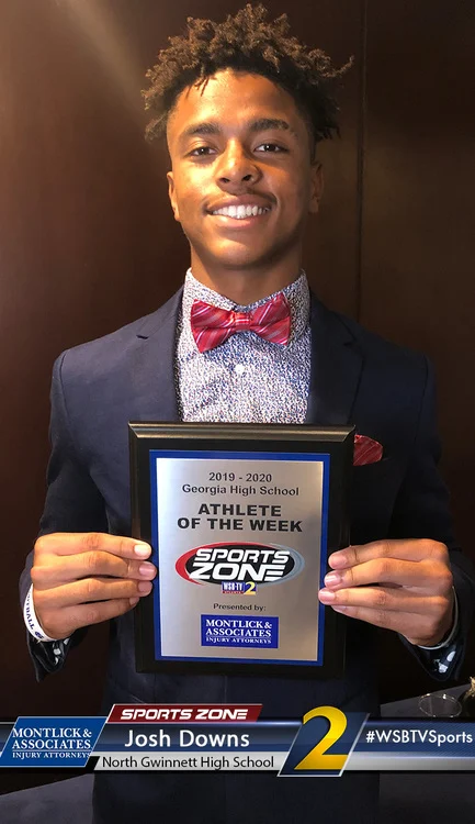 Smiling athlete holding Sports Zone Athlete of the Week award, representing achievement in high school sports.
