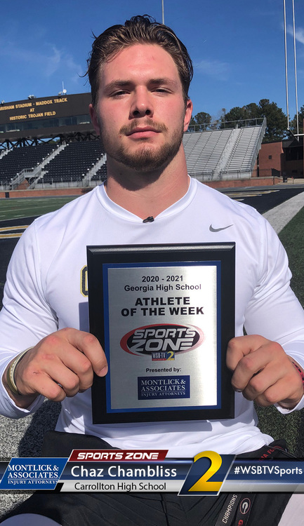 Alt text: High school athlete of the week Chaz Chambliss holding sports zone award on football field