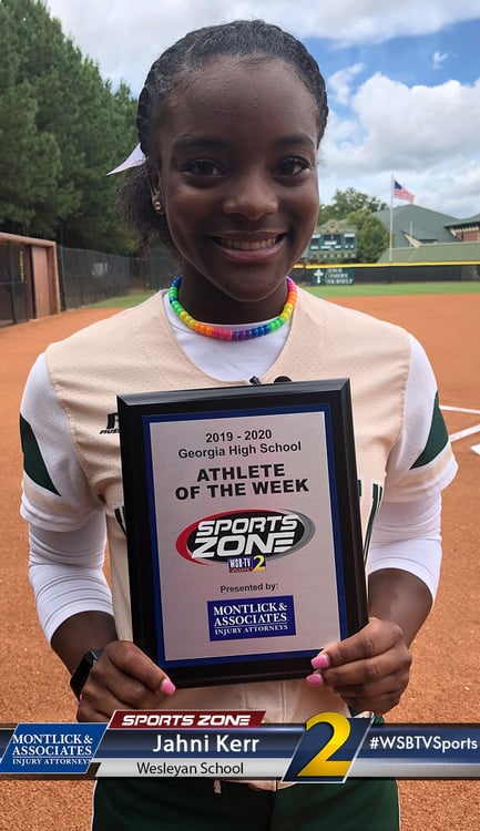 Smiling young student athlete of the week holds award plaque on school sports field