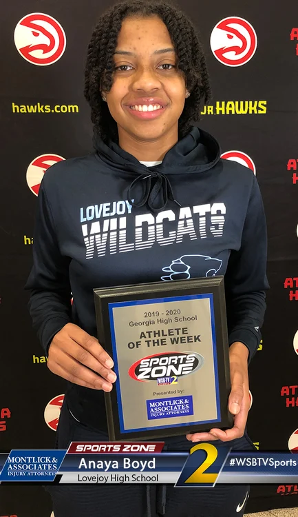 Smiling student athlete of the week holding award plaque. "Love Joy Wildcats" on black hoodie.