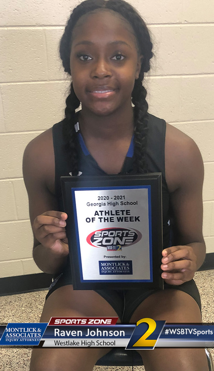 Young African American female student athlete holding high school sports award plaque smiling proudly.
