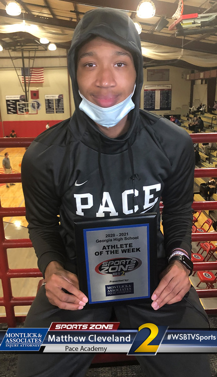 Young student athlete holding Sports Zone Athlete of the Week plaque at Pace Academy, wearing mask and hoodie.
