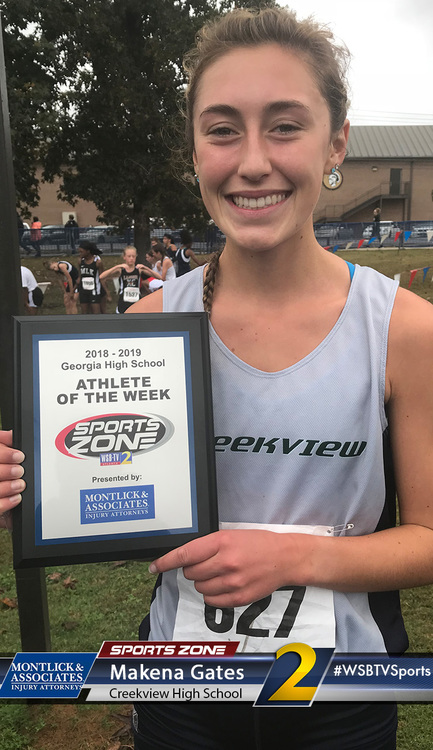 Smiling high school athlete of the week holds award plaque on sports field, sponsored by local business
