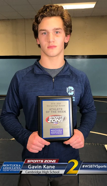 Young male student athlete of the week holding award plaque at Cambridge High School sports event.