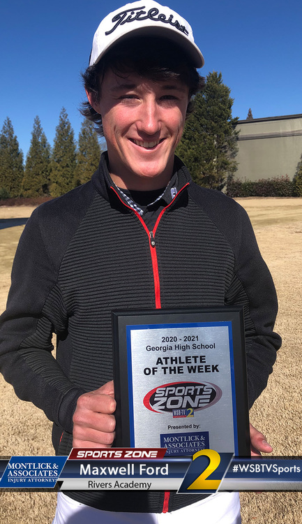 Smiling male golfer holding award plaque for Athlete of the Week at golf course wearing hat and jacket