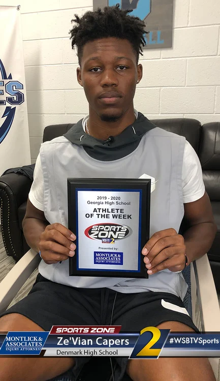 High school athlete of the week holds award certificate from a sports broadcaster while sitting on a bench.