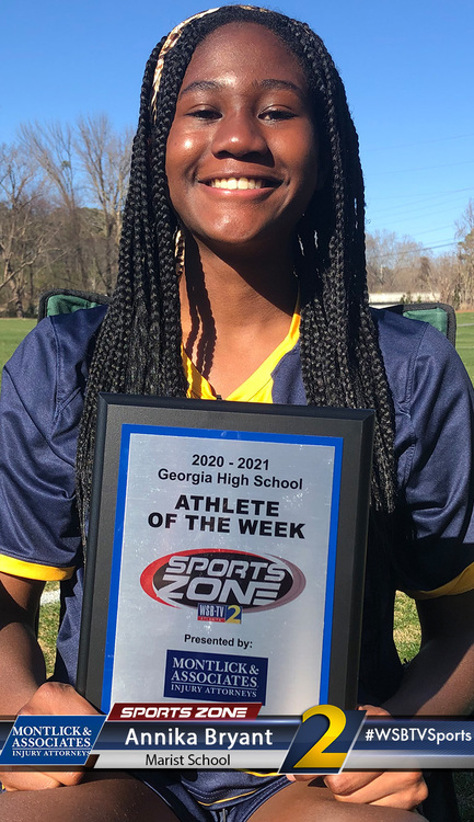 Smiling high school athlete holds sign for Athlete of the Week award from local sports news program.