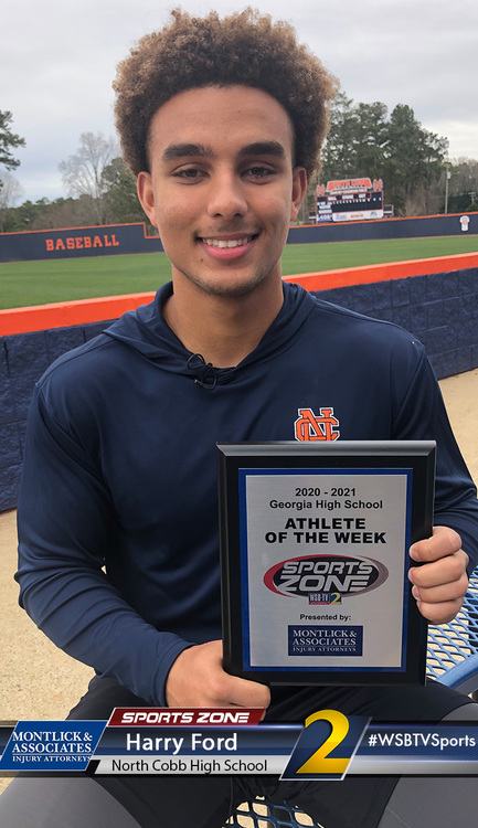 Smiling North Cobb High School athlete of the week holds Sports Zone award plaque on baseball field