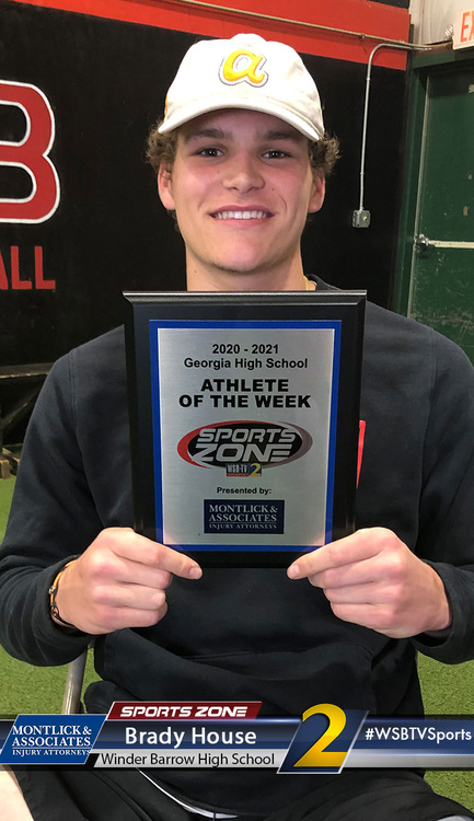 Smiling athlete holding Sports Zone Athlete of the Week award plaque, sponsored by local high school.