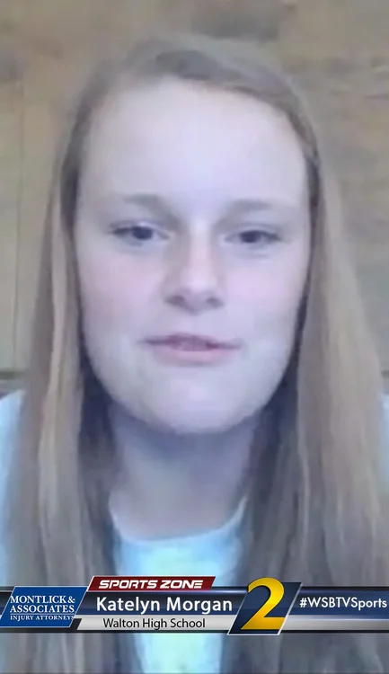 Blurred photo of a young woman with blonde hair and blue shirt, looking directly at the camera.