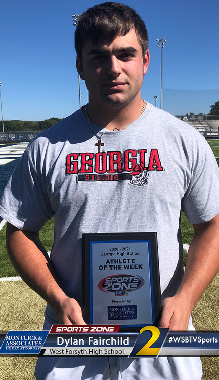 Alt text: High school athlete of the week Dylan Fairchild holds trophy on football field, Georgia Bulldogs shirt