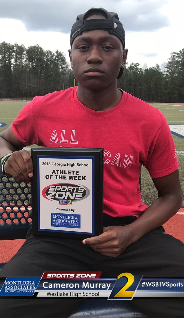 High school athlete holding Athlete of the Week award plaque on a sports field