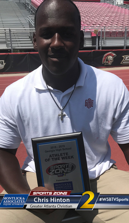 Alt text: Smiling high school athlete of the week holds Sports Zone award plaque on sports field