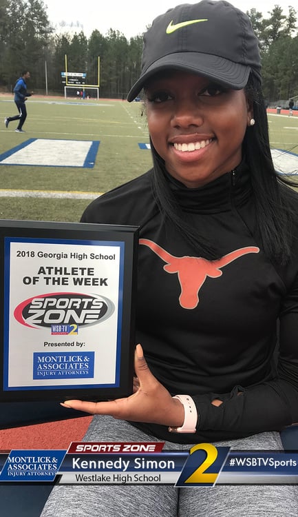 Westlake High School athlete of the week Kennedy Simon smiling and holding Sports Zone award on football field