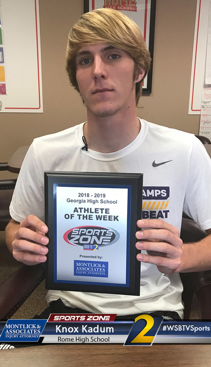 Athlete of the Week award winner at Sports Zone injury attorney office, smiling while holding plaque.