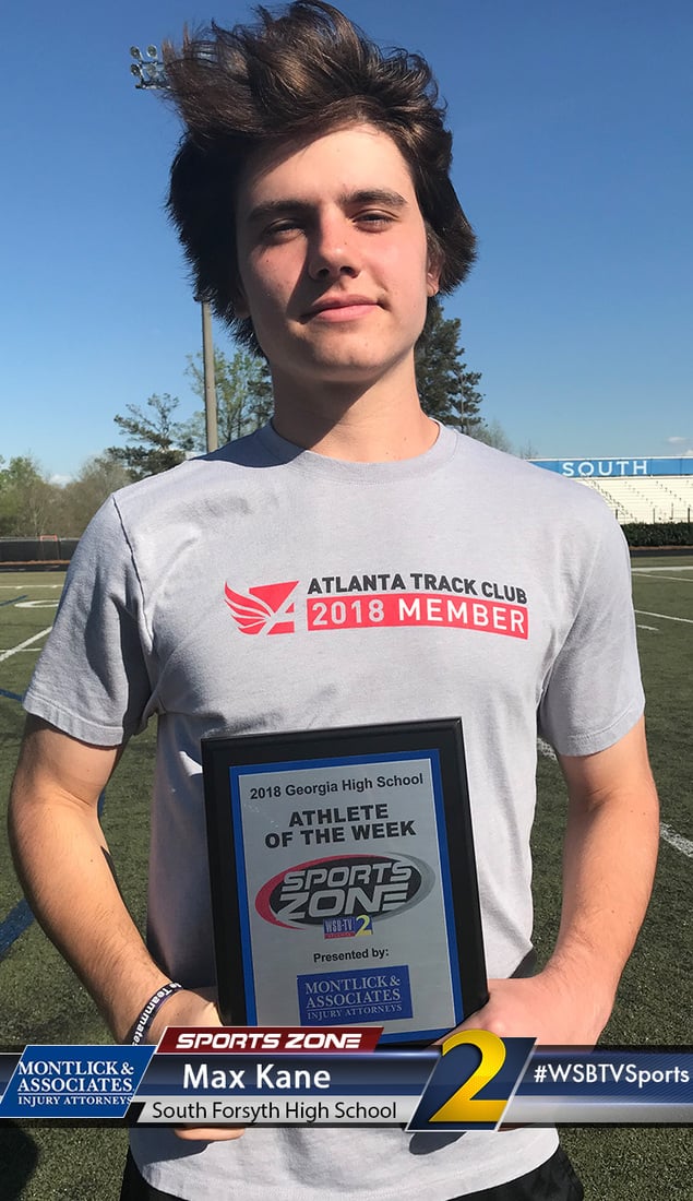 Young male athlete smiling while holding 2018 Athlete of the Week award on a football field.