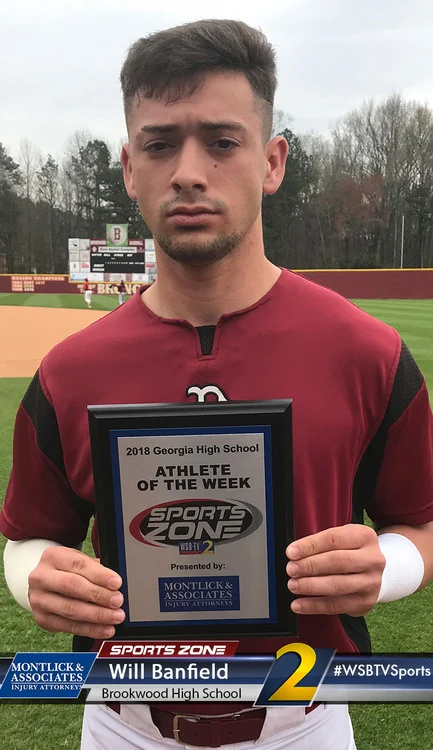 High school athlete holding Athlete of the Week award on baseball field, presented by injury attorneys