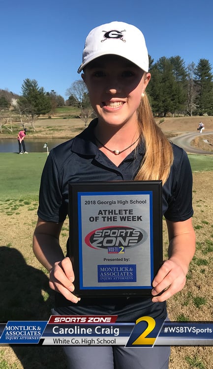 High school golfer holding Sports Zone Athlete of the Week award plaque while smiling on golf course