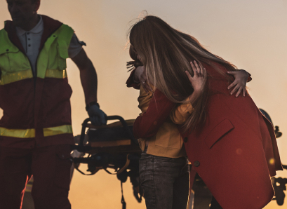 Alt text: Woman in wheelchair being pushed by paramedic, sunset background, representing injury assistance