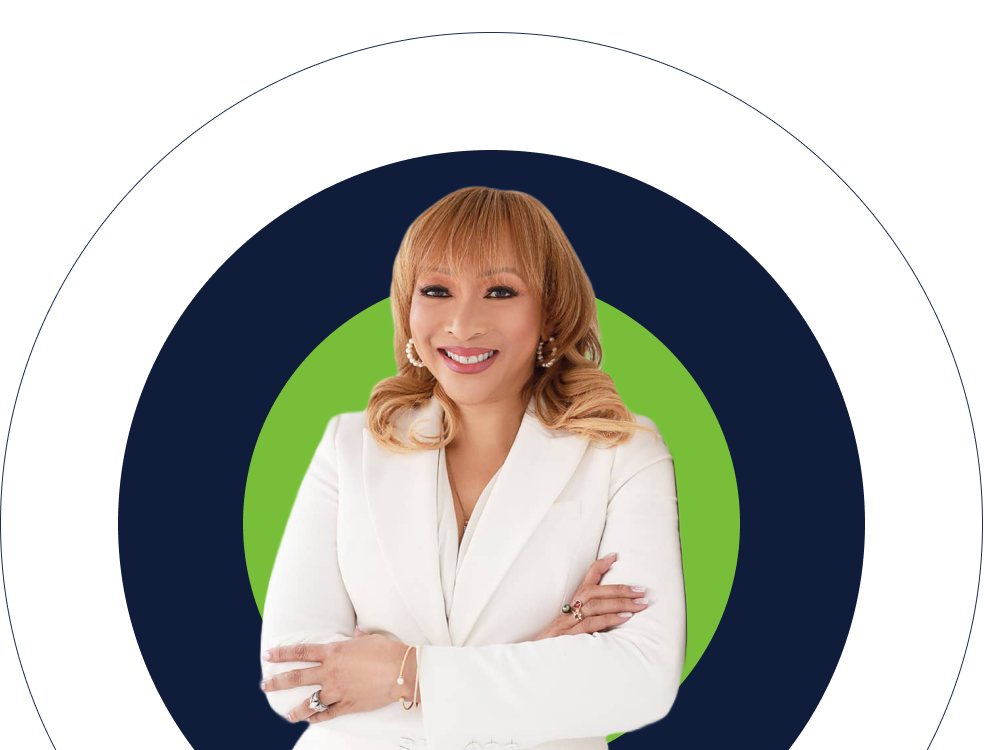 Smiling blonde woman in white blazer against green and navy background, arms crossed confidently.