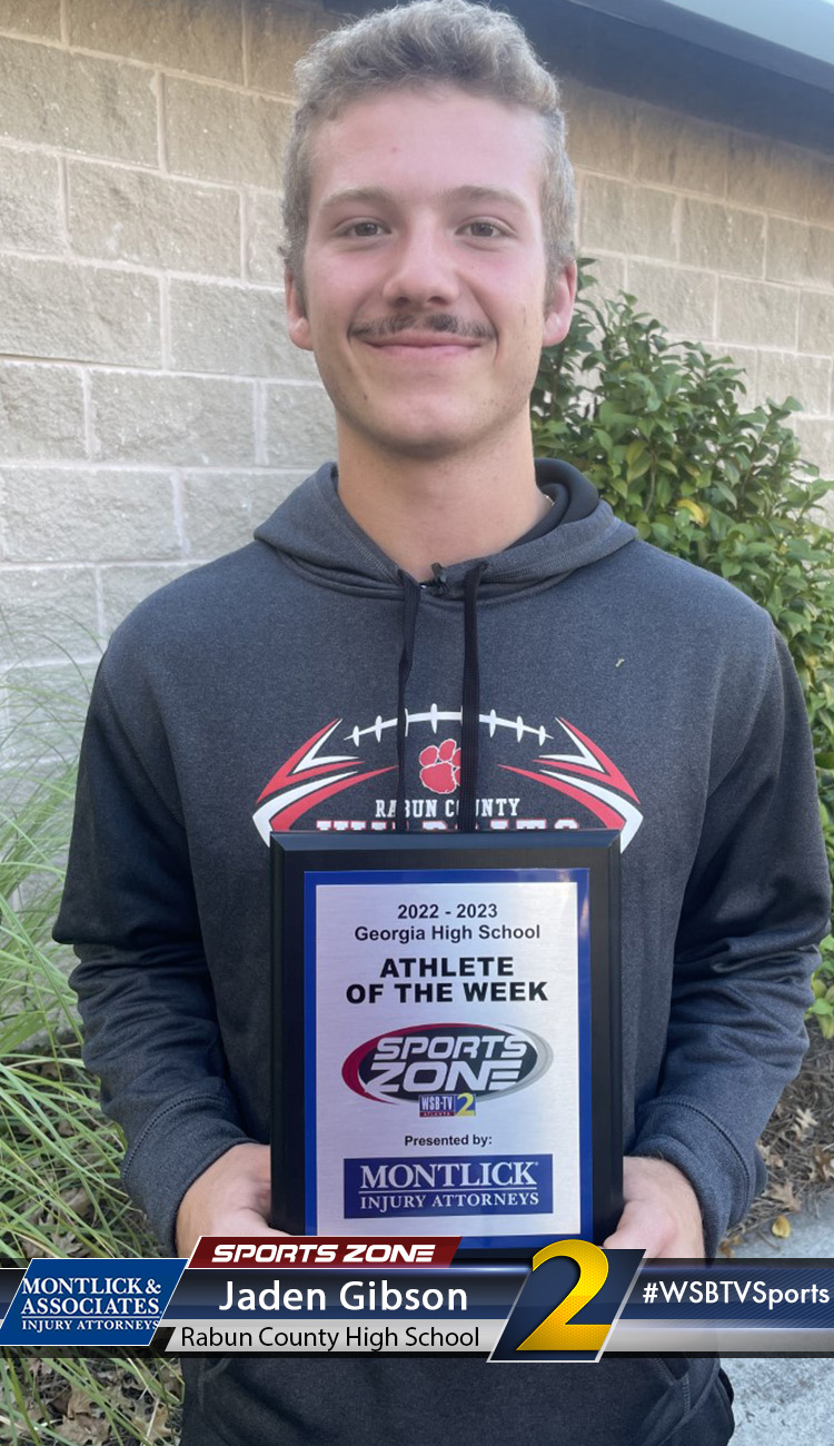 Smiling high school athlete holding Sports Zone Athlete of the Week award