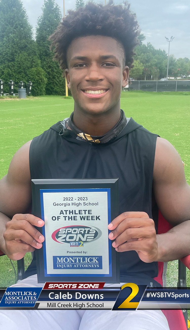 Young male student athlete holding sports award plaque while smiling