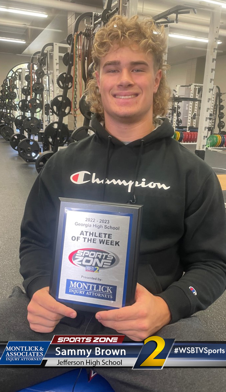 Smiling high school athlete holding Sports Zone Athlete of the Week award