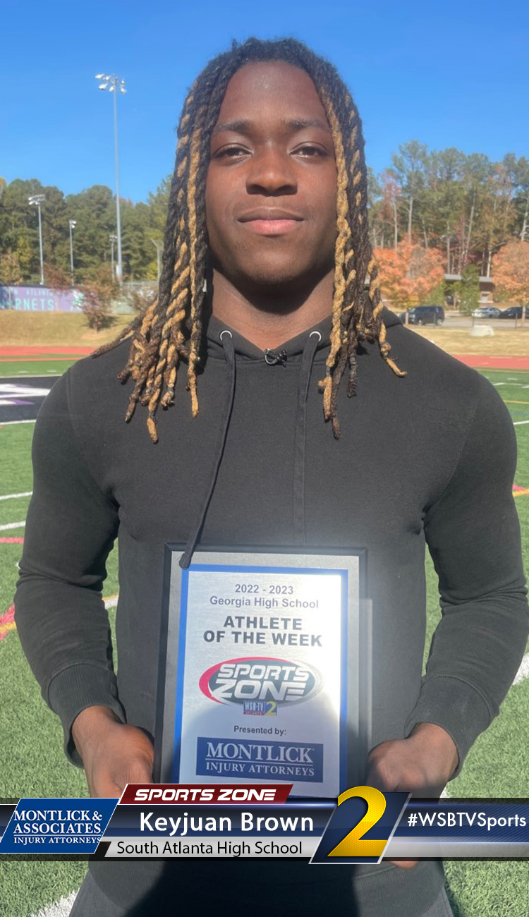 Smiling high school athlete holding Sports Zone Athlete of the Week award