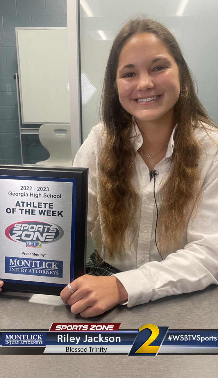 Smiling high school athlete holding Sports Zone Athlete of the Week award