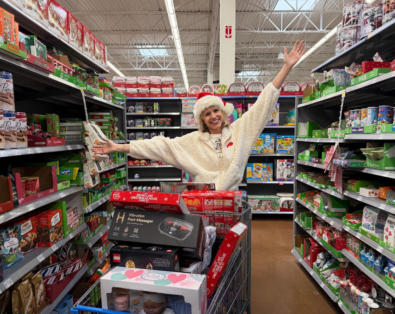 Jenny Harty of Montlick posing in a store with hands outstretched as she loads up a cart of holiday gifts for families.