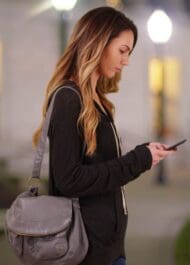 a young woman booking a rideshare at night