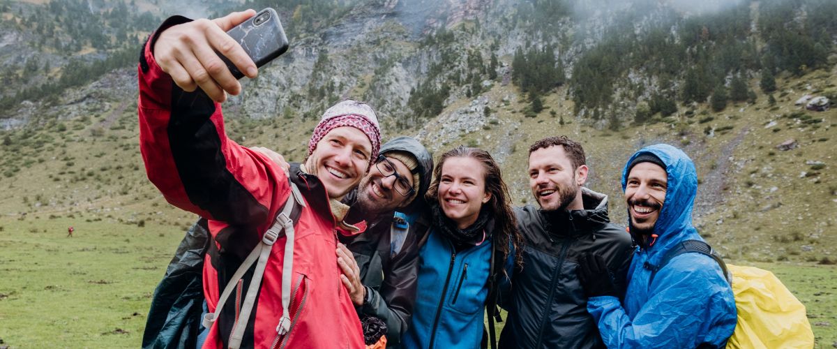 A group of friends on a hike in the mountains taking a group selfie